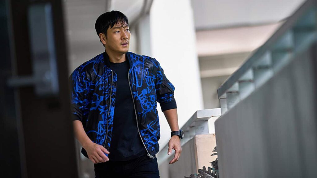 A man moves cautiously through a modern building during a tense survival moment in the South Korean disaster film